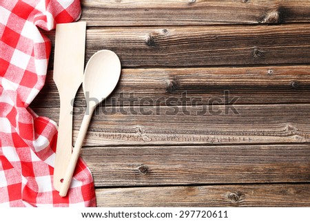 Empty wooden table with wooden spoon and napkin on brown background