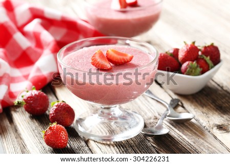 Tasty strawberry mousse in glass on brown wooden table
