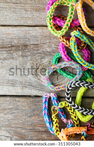 Colorful rubber band bracelets on grey wooden background
