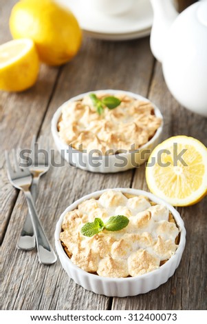 Lemon meringue pie in bowl on grey wooden background
