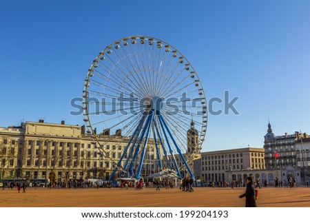 LYON, FRANCE - DEC 23, 2013: people by the giant ferris wheel at Bellecour square in Lyon France