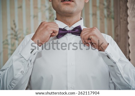 The young man dresses a tie - a butterfly.