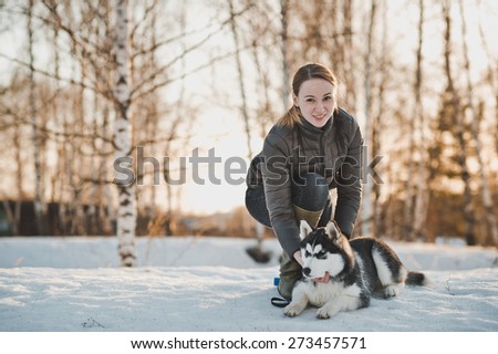 The girl walks with a dog in the winter.