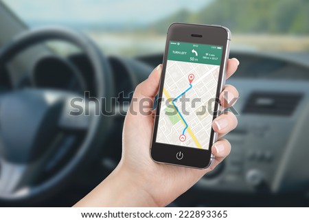 Female driver sitting in the car and holding black mobile smart phone with  map gps navigation application with planned route on the screen. Blurred car  interior on the background. - Stock Image -
