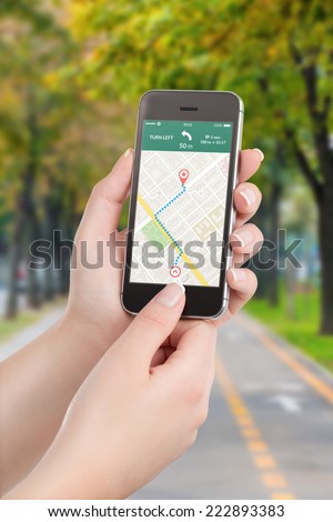 Female hands holding black mobile smart phone with map gps navigation application with planned route on the screen. Blurred street view on the background.