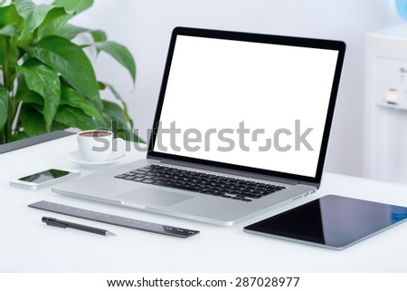 Modern office workspace with laptop computer, tablet pc and smartphone on the desk. There is a laptop, tablet computer, smartphone, cup of coffee on the table. For design presentation or portfolio.