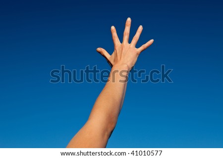 Outstretched arm of a young woman under blue sky.
