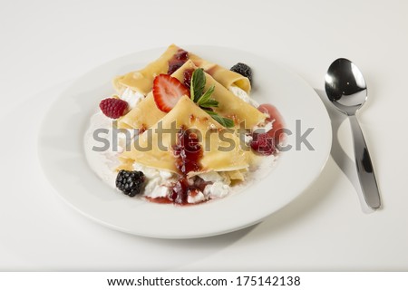 Crepes with strawberry and blackberry stuffed with cheese with marmalade and jam. Full shot with spoon