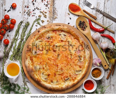 Pizza with mushrooms and cheese red hot pepper spices spoon and fork on a wooden background