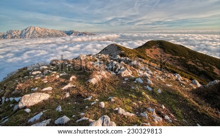 The view of the mountains above the clouds from the Srednji vrh mountain with the Kamnik-Savinja Alps in the background at dusk, Slovenia
