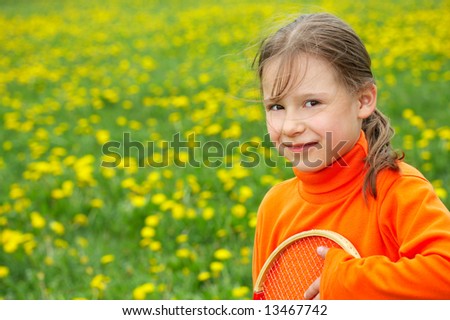 The little girl in orange clothes holds a tennis racket