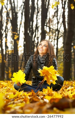 ? beautiful woman in an autumn park collects leaves