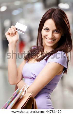Portrait of the beautiful happy girl in the shop, holding in a hand a credit card