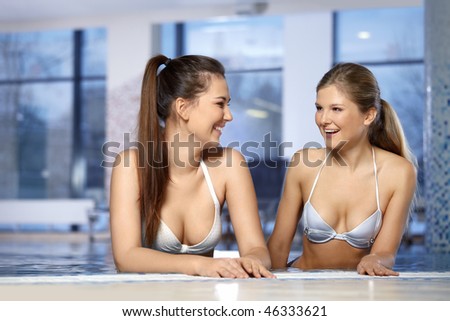 Two attractive young girls laugh in pool