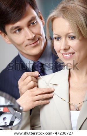 The man helps to try on to the woman of a necklace
