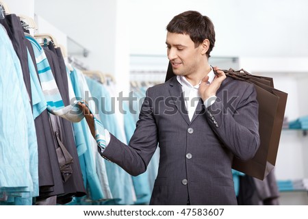 The young man chooses clothes in shop