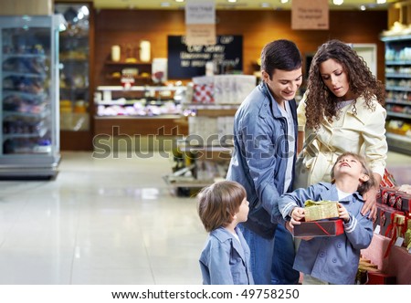 Happy family with boxes of gifts in shop in the foreground