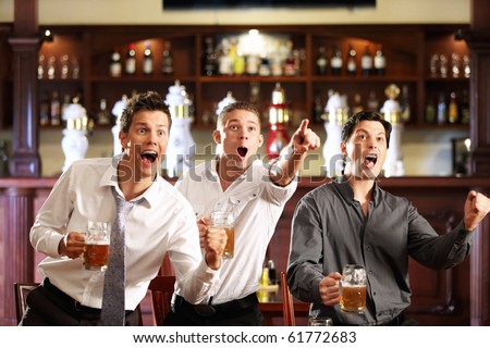 Three men with beer rejoice the victory of their favorite team in the pub