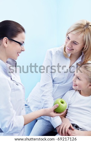 The doctor gives the child a green apple