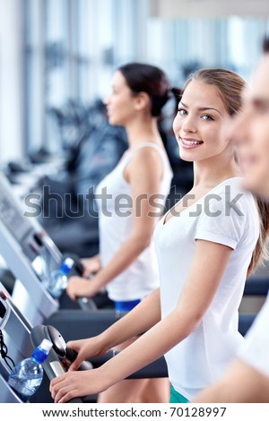 Attractive young girl on a treadmill in fitness club