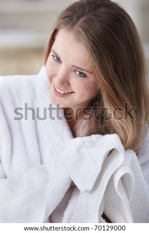 A young girl in a white coat dries hair with a towel