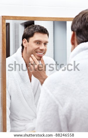 The young man looks in the mirror in the bathroom