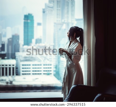 Beautiful girl at the window of the apartment