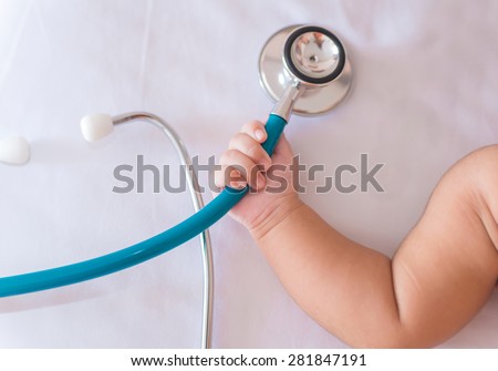medical instruments stethoscope in hand of newborn baby girl.