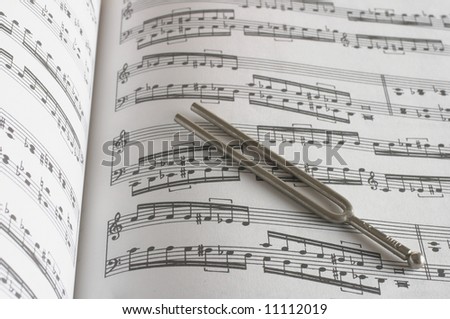 Tuning fork on classic sheet music background