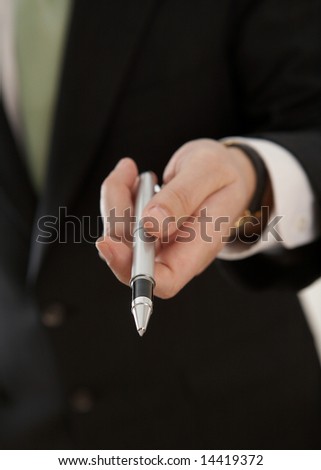 Hand of businessman offering pen to sign contract