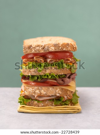 Stacked deli sandwich with fresh turkey, roast beef, tomato, lettuce, and cheese
