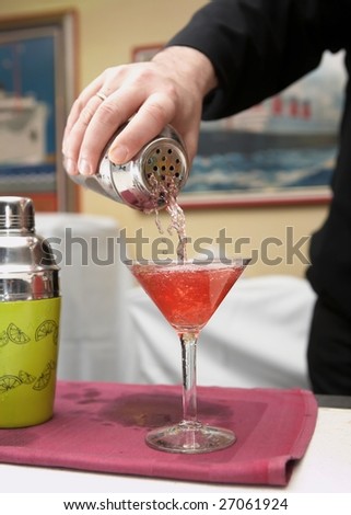 Bartender pouring red martini from cocktail shaker