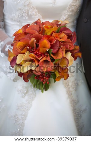 Bride holding wedding bouquet of calla lilies against dress