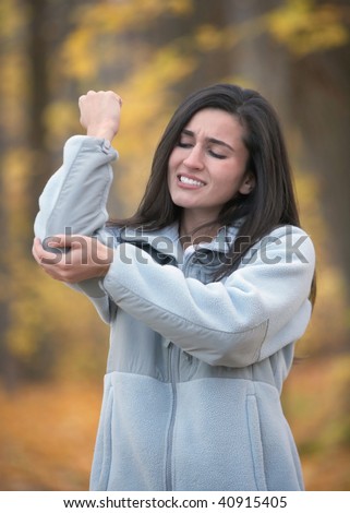 Young woman with elbow pain outdoors in autumn