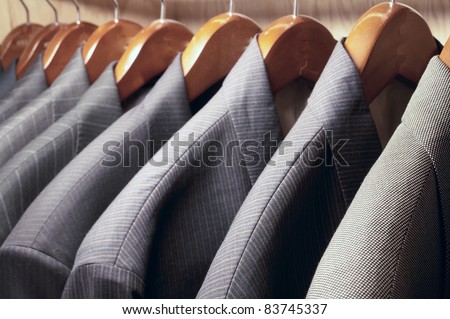 Row of men\'s suit jackets hanging in closet