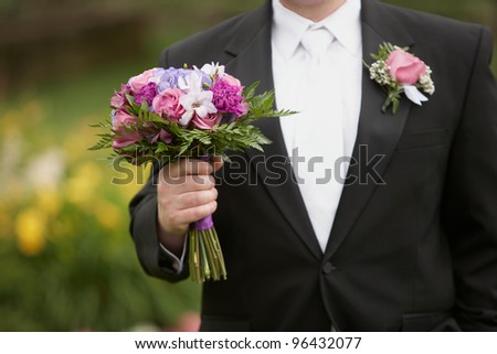 Wedding groom with bride\'s bouquet of flowers outside