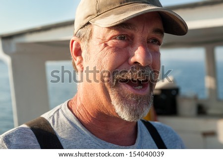 Older, caucasian, bearded Lobster fisherman talking and looking off to the side, Maine, USA