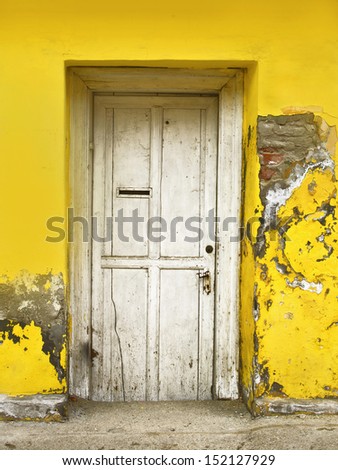 Old white wooden door on yellow house.