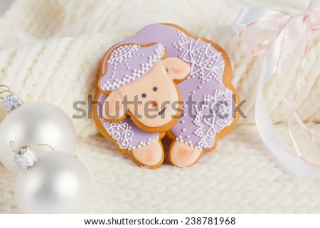 Lavender color gingerbread sheep with Christmas decoration on white knitted background