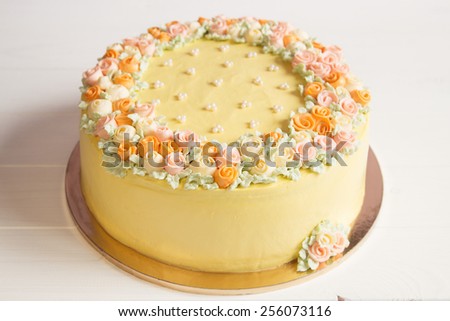 Pale yellow mousse cake with pastel cream flowers on white background