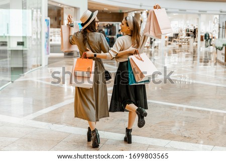 Shopping and entertainment, mall inside. Two beautiful girls with paper bags at the mall. The joy of consumption, Gift shopping, holiday