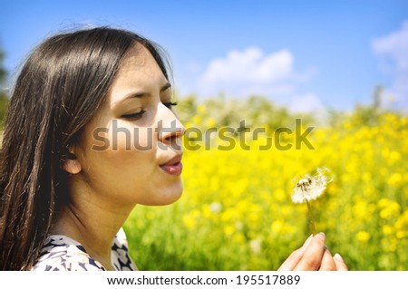 Blowing a dandelion. A beautiful young woman blowing a dandelion.