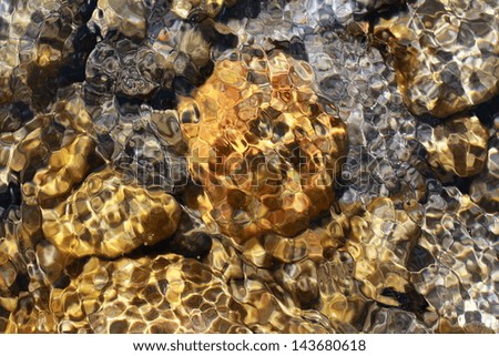 golden stones in the river with sunbeam and moving water