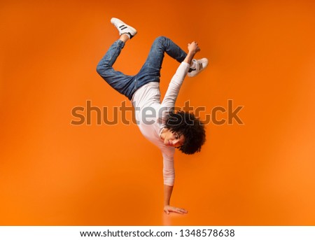 Black awesome man balancing on one hand on orange background 商業照片 © 