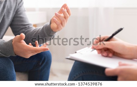 Psychotherapist writing notes, assessing patient's health and giving diagnosis to man sitting on couch during counseling session , panorama, free space Foto d'archivio © 