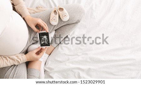 Pregnant woman enjoying future motherhood with first ultrasound photo of her baby, top view with free space Stockfoto © 