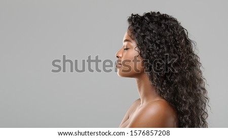 Hair extension concept. Profile portrait of beautiful curly african american woman over gray background, panorama with free space