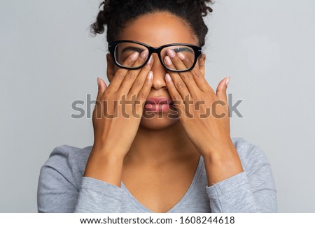 African girl in glasses rubs her eyes, suffering from tired eyes, ocular diseases concept Stok fotoğraf © 