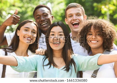 Selfie Fun. Group of multi-ethnic teen friends taking self portrait picture outdoors and sincerely smiling at camera Stock foto © 