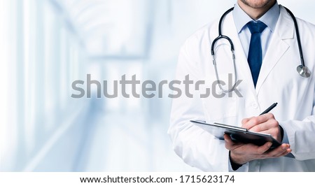 Quality Medical Services. Unrecognizable Male Doctor In Uniform Taking Notes To Clipboard While Standing In Hospital Corridor, Cropped Image, Panorama Stock fotó © 